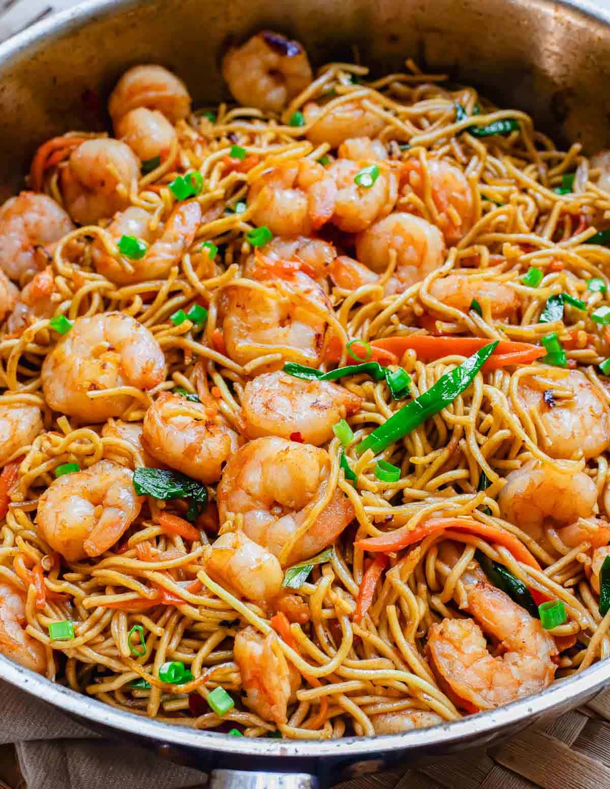 Shrimp lo mein in a stainless steel wok.