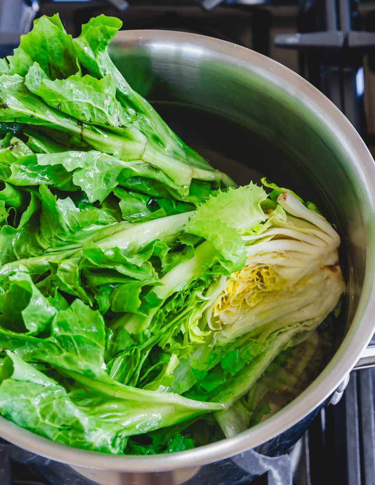 Escarole in a pot on top of a stove.