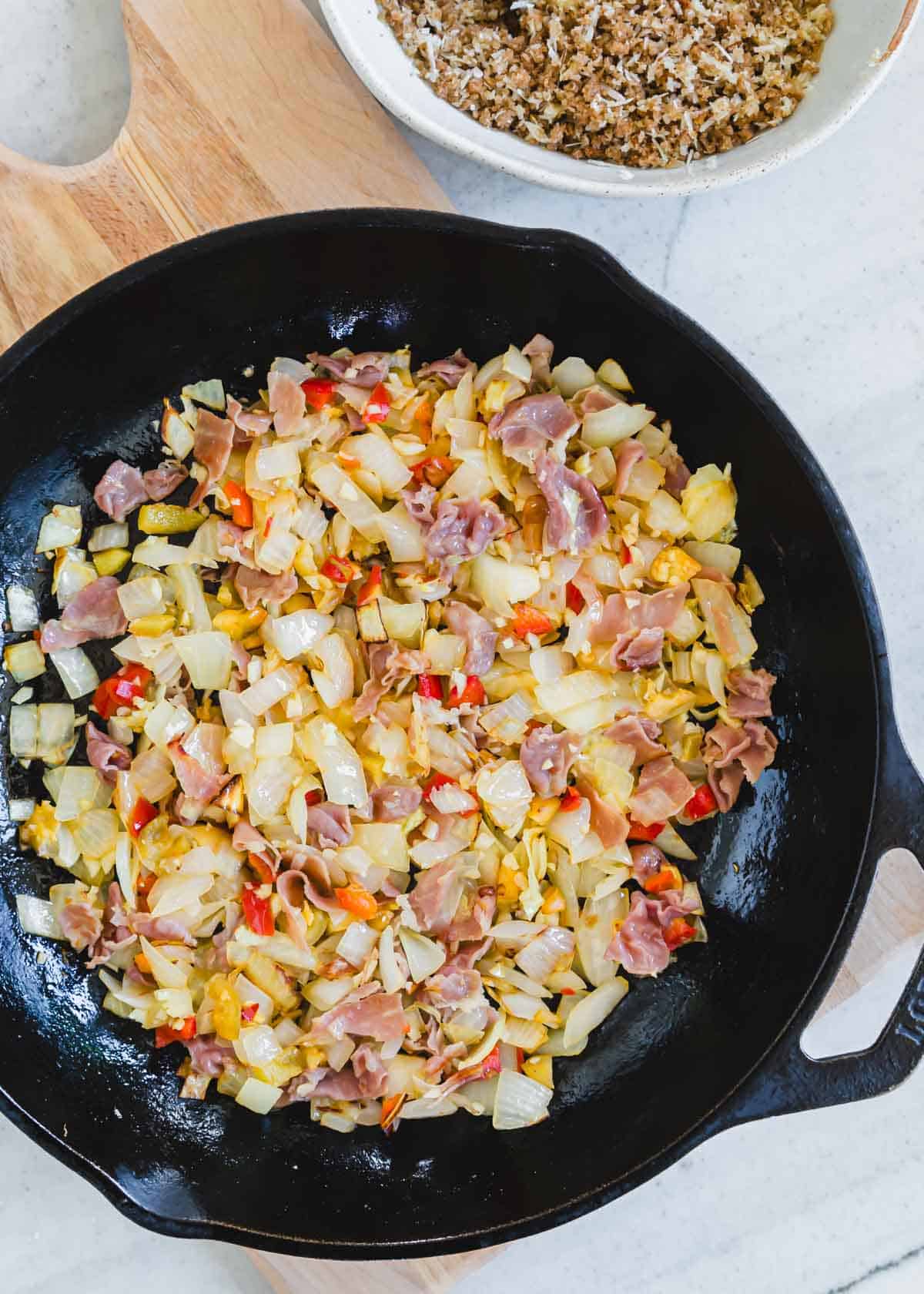 Sauteed onions, garlic, prosciutto and pickled hot cherry peppers in a cast iron skillet.