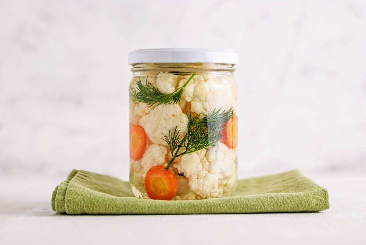 A jar with fermented cauliflower and carrots in it.