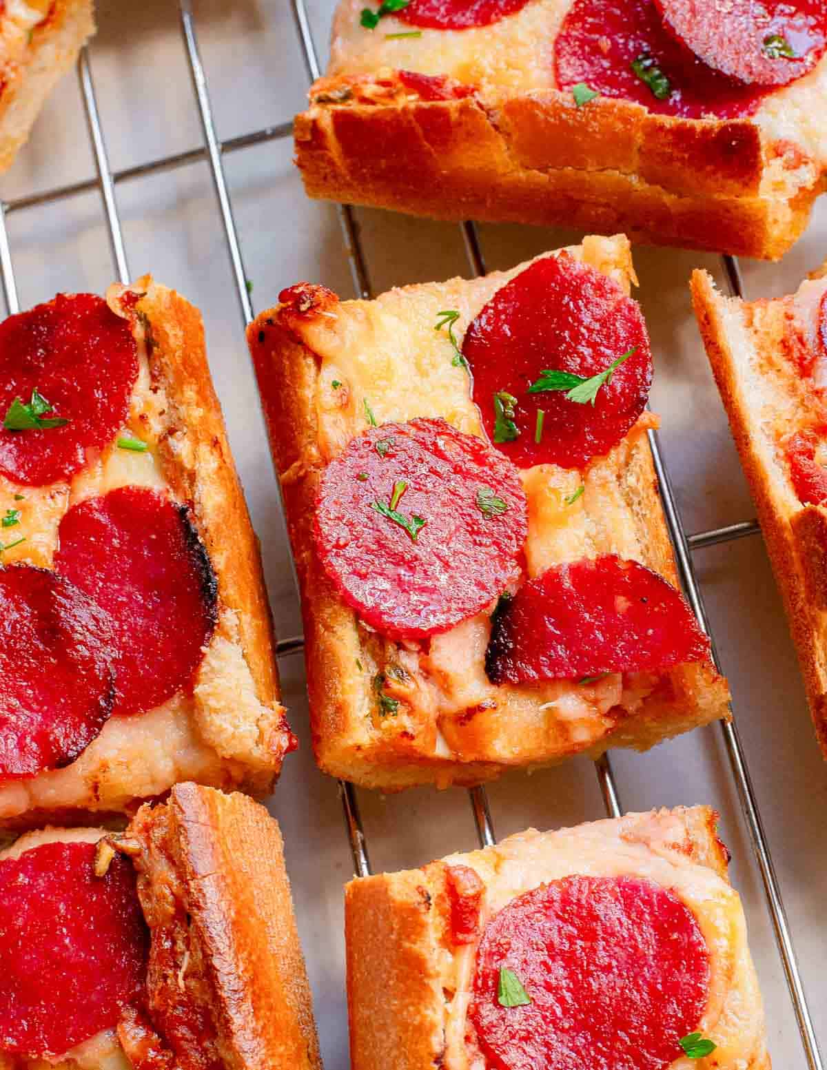 Pepperoni French bread garlic pizza cut into squares on a cooling rack.
