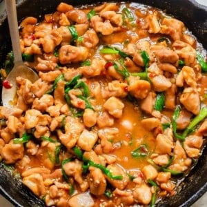 Chinese gochujang chicken in a cast iron skillet with a metal serving spoon.