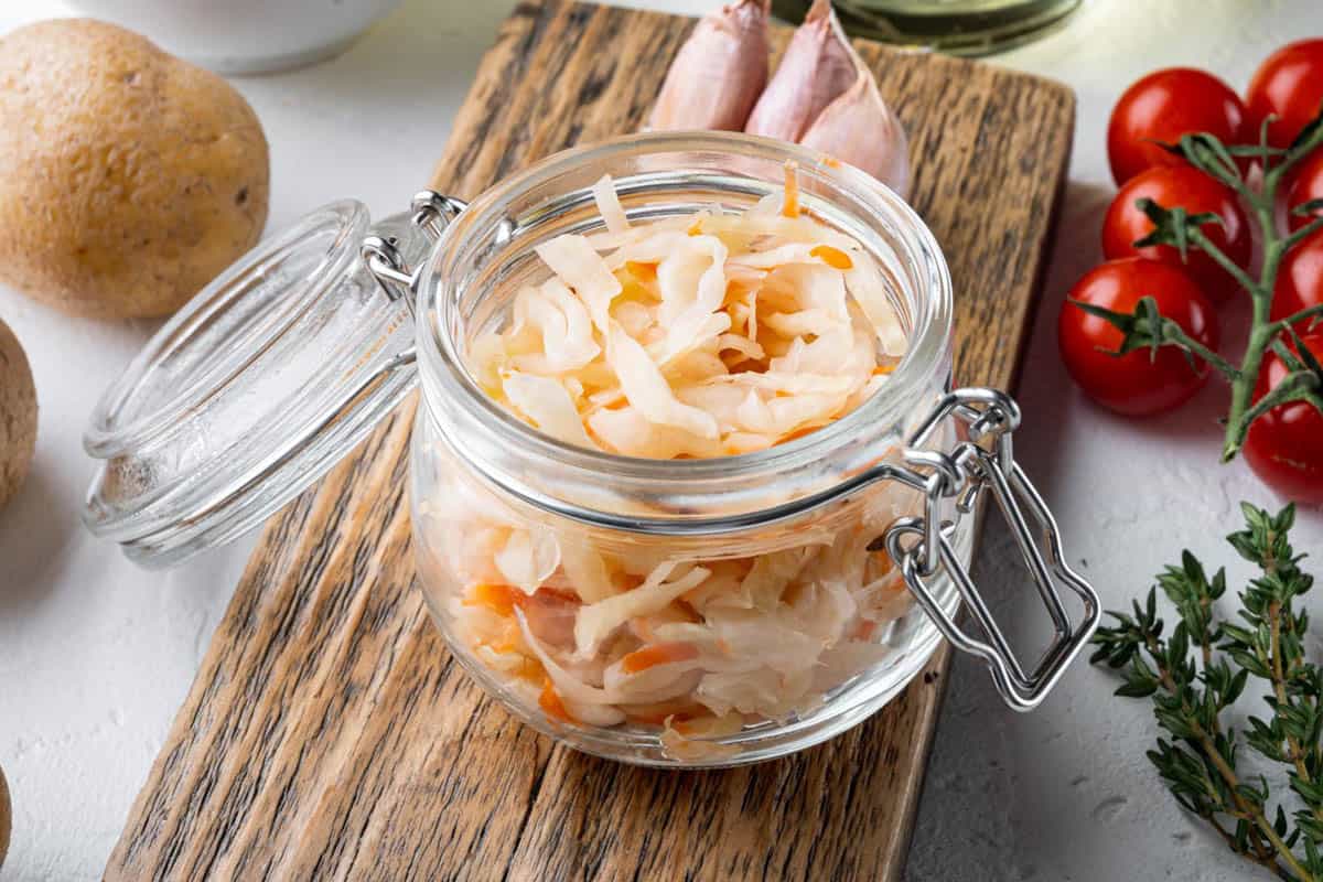 Sauerkraut in a glass jar with tomatoes and potatoes.