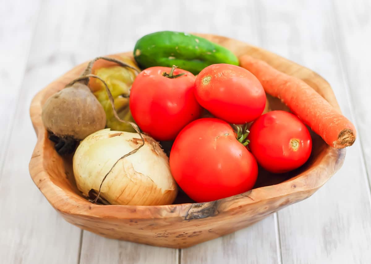Fresh vegetables in a wooden bowl on a white background.