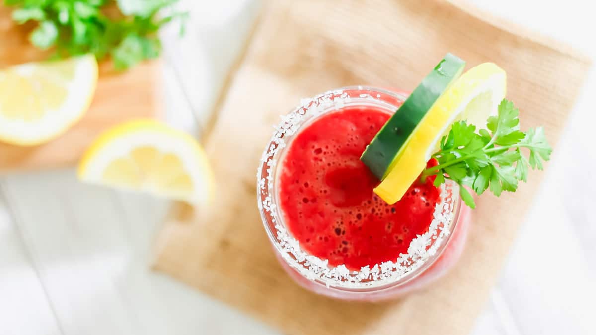 Homemade V8 juice recipe in a salt rimmed glass on a wooden table.