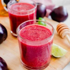 Two glasses of plum juice on a cutting board.