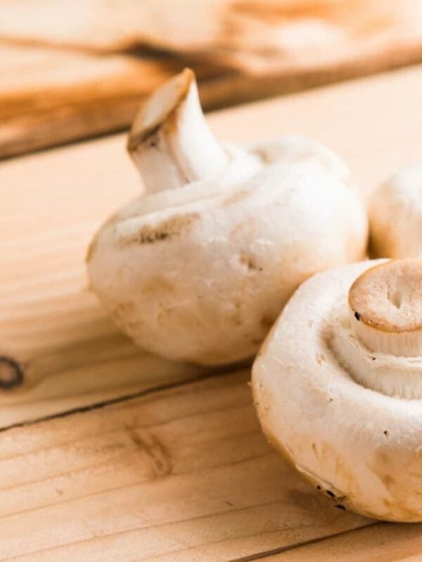 White button mushrooms on a wooden surface.