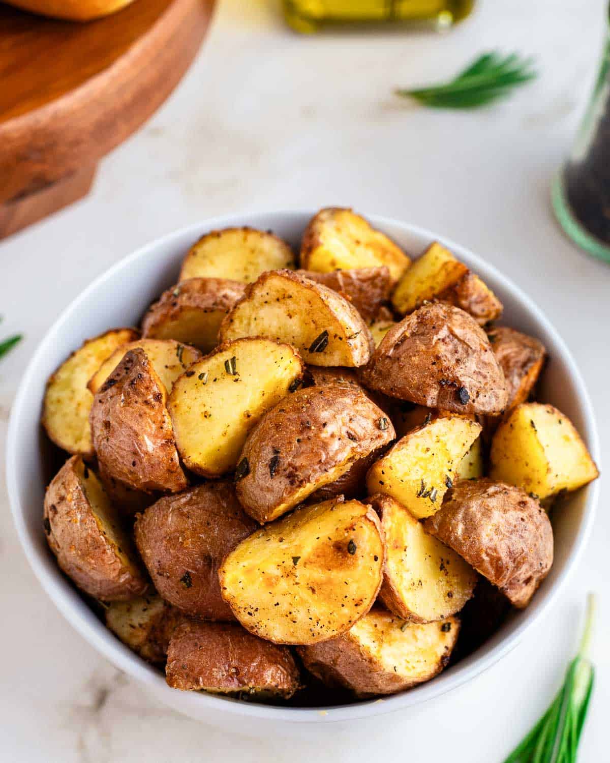 Close up of air fryer roasted red potatoes in a white bowl.