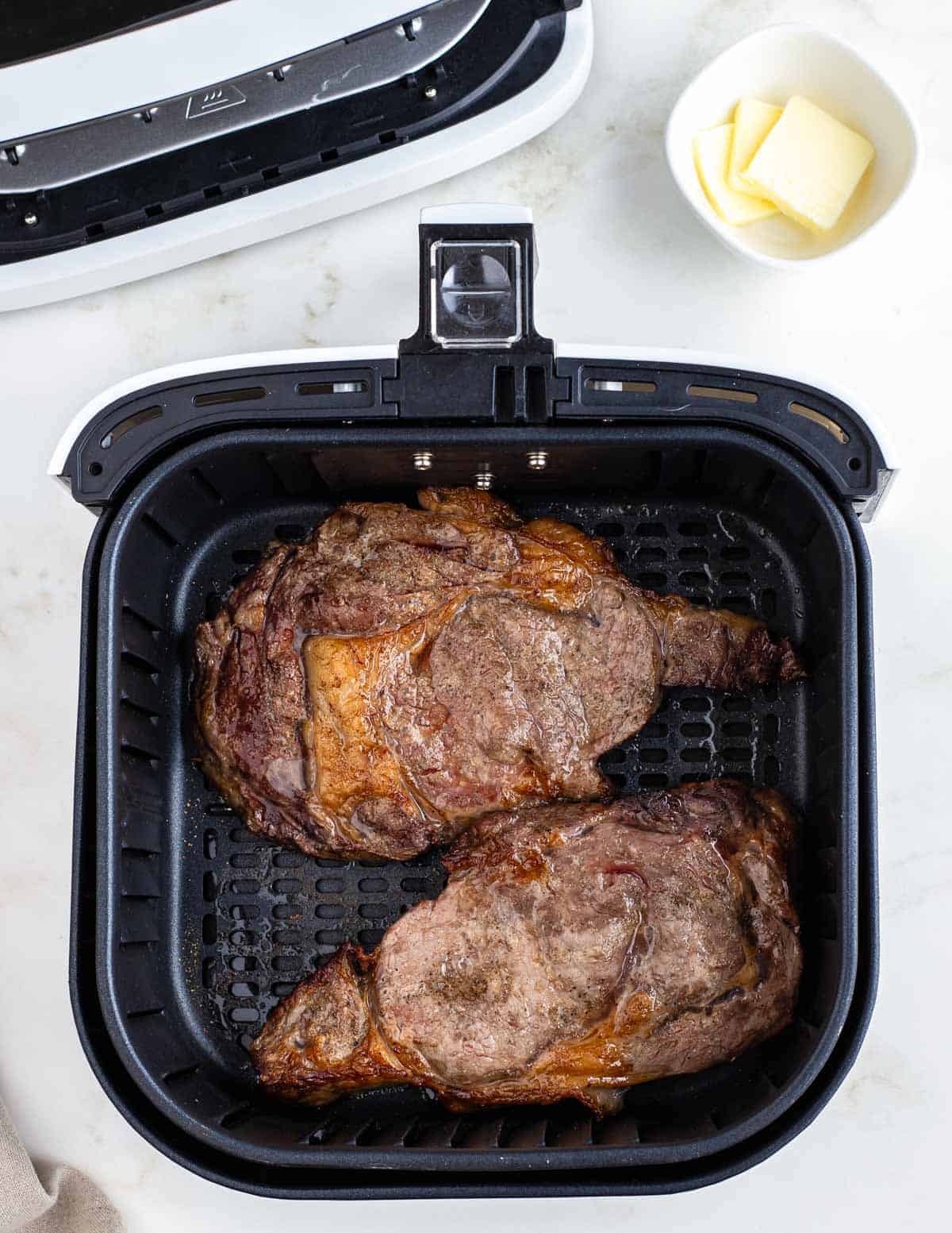 Cooked ribeye steaks in an air fryer.