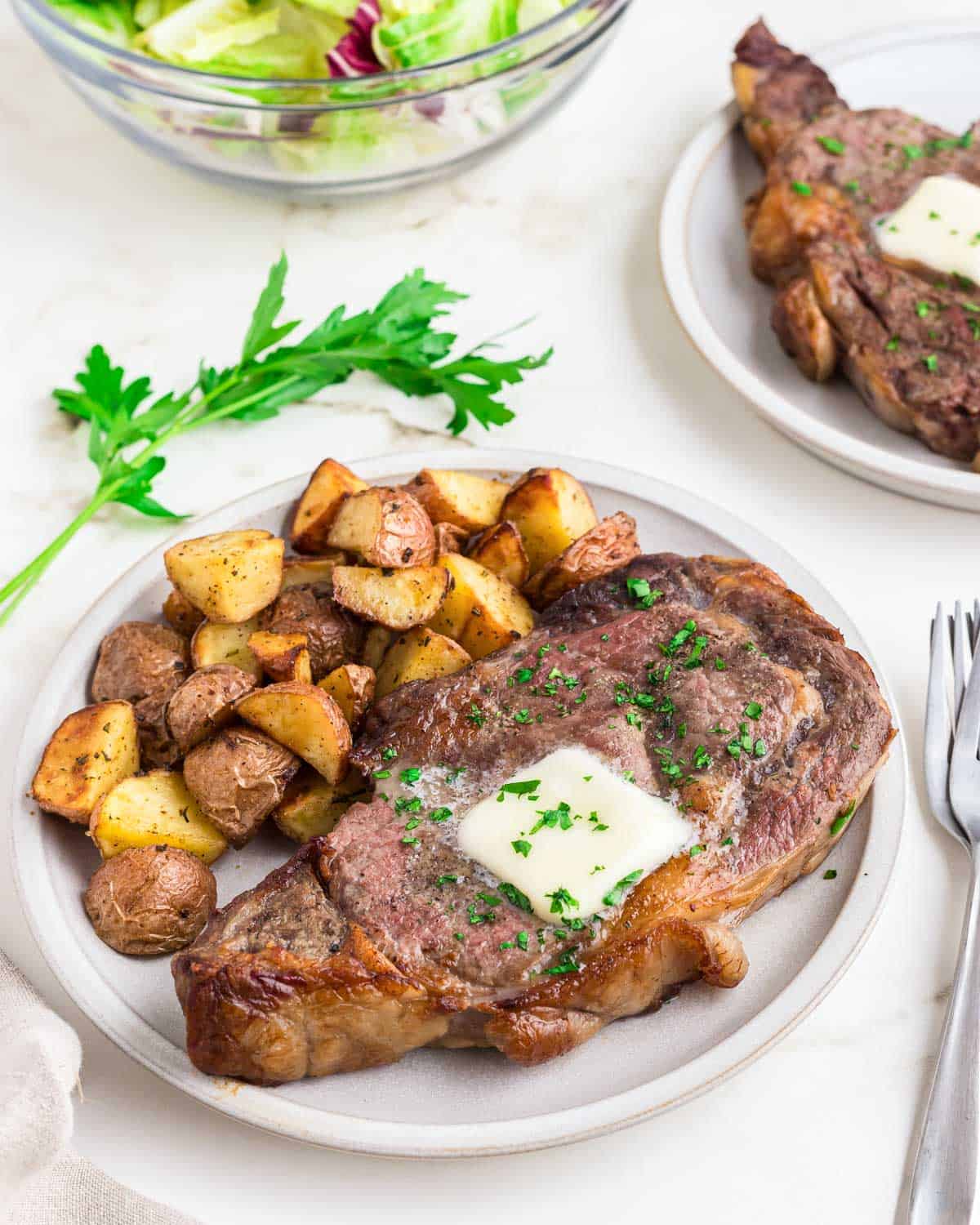 Air fryer ribeye plated with roasted red potatoes.