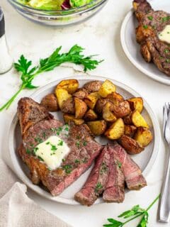 Sliced air fryer ribeye recipe with potatoes on a white plate.