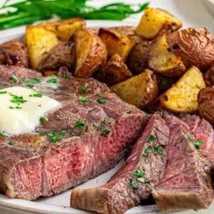 Head on shot of sliced medium-rare air fried ribeye steak with melted butter and parsley.