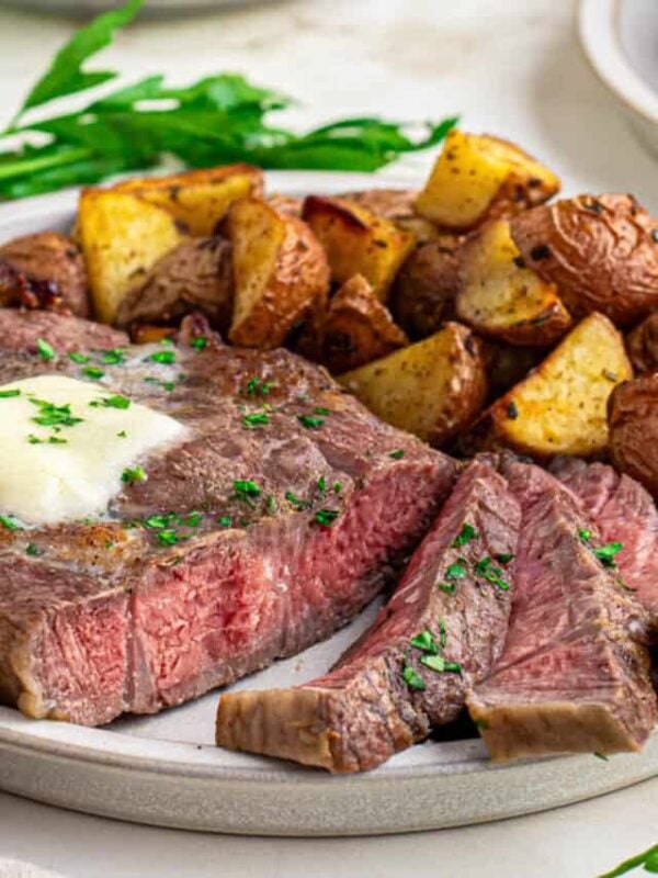 Head on shot of sliced medium-rare air fried ribeye steak with melted butter and parsley.