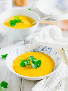 Pumpkin potato soup in a blue and white bowl garnished with fresh parsley.