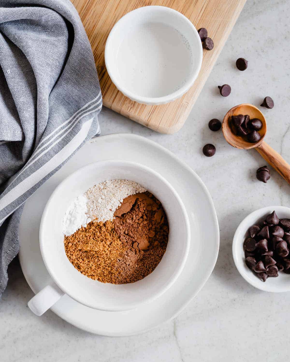 Ingredients to make a chocolate protein mug cake in a white mug.