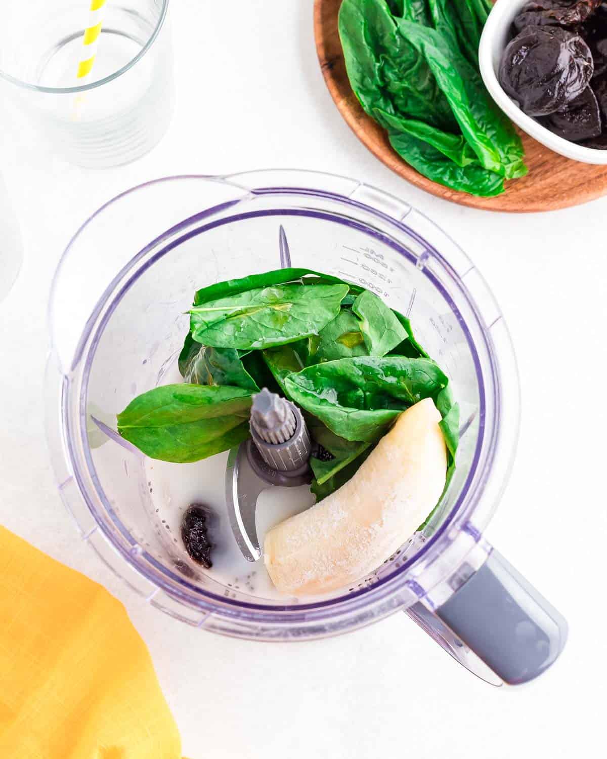 Prune smoothie ingredients in a blender on a white surface.