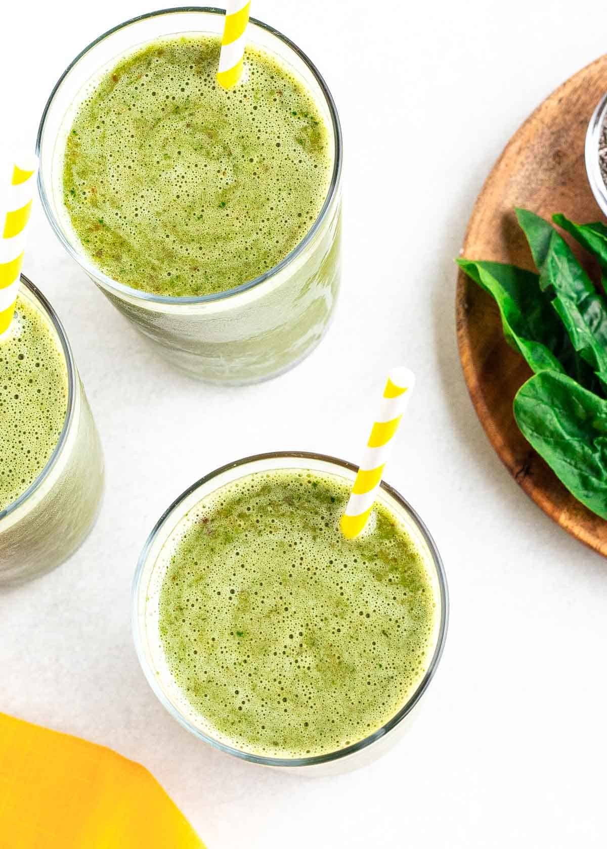 Overhead shot of green prune smoothies with yellow striped straws.