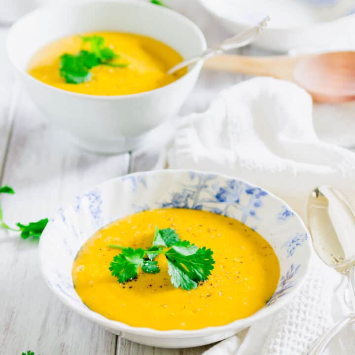 Pumpkin potato soup in a blue and white bowl garnished with fresh parsley.