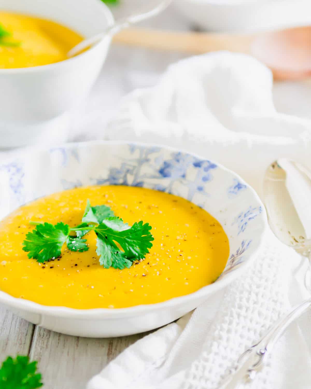 Blender pumpkin potato soup in a blue and white bowl with fresh parsley.