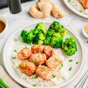 Garlic ginger soy salmon bites made in the air fryer served with white rice, broccoli and scallion garnish.