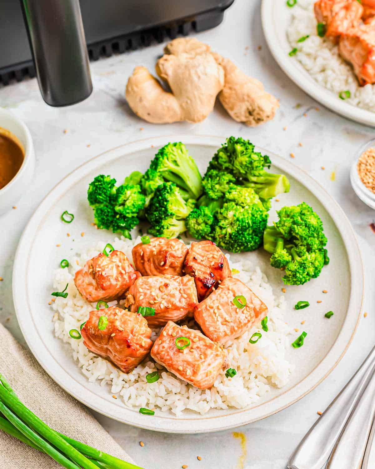 Garlic ginger soy salmon bites made in the air fryer served with white rice, broccoli and scallion garnish.