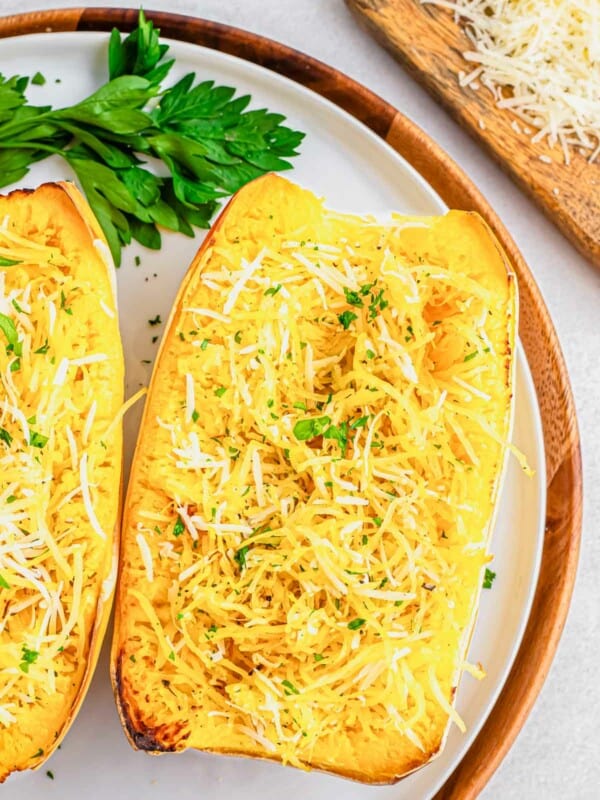 Air fryer spaghetti squash recipe with parmesan cheese on a white plate with parsley.