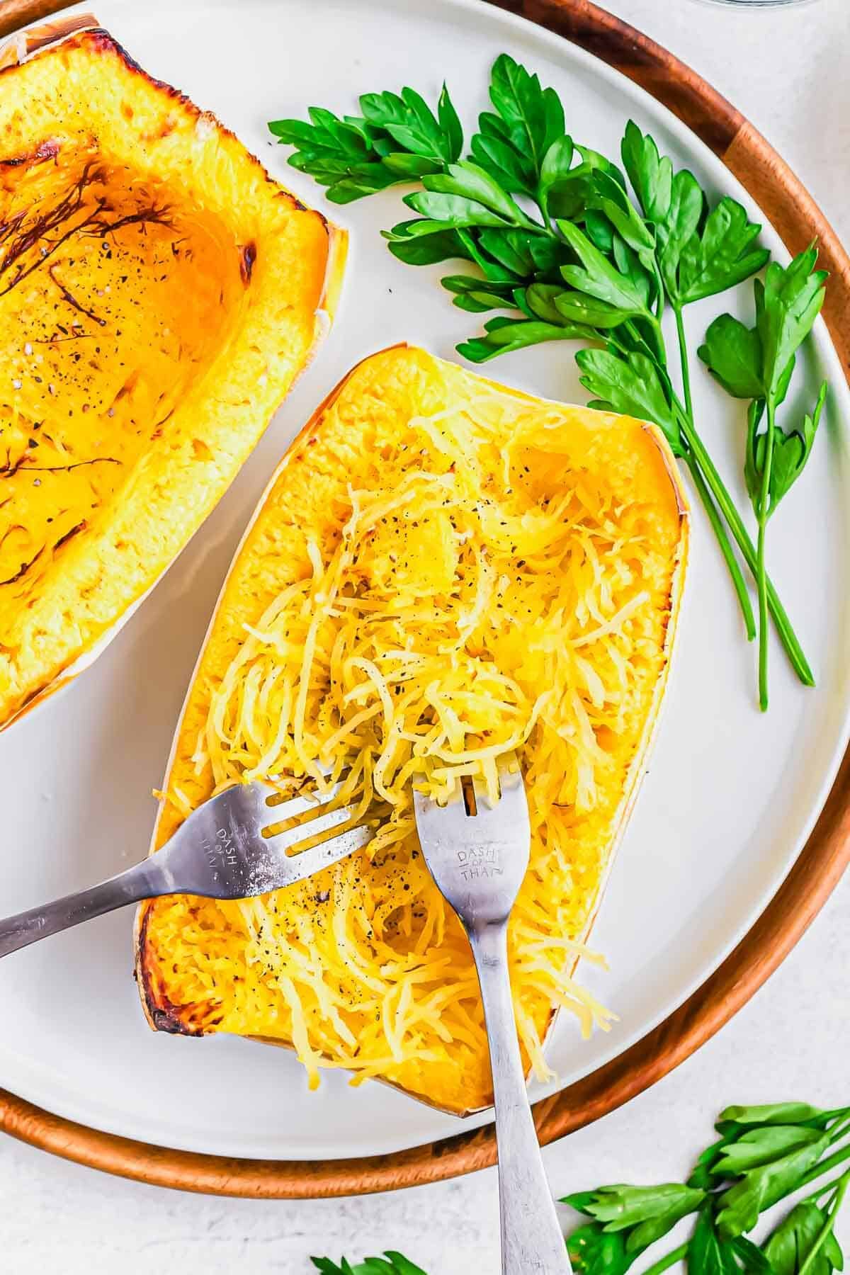 Air fryer roasted spaghetti squash on a plate with two forks and fresh parsley.