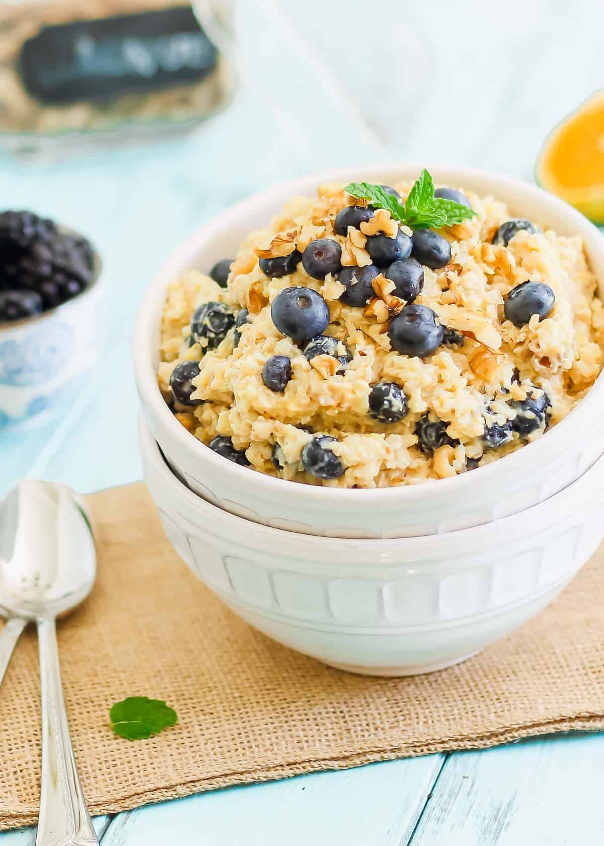 Breakfast grain bowl with fresh blueberries a mint in a white bowl.