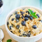 Breakfast grain bowl recipe with chopped walnuts and blueberries in a white bowl.