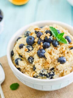 Breakfast grain bowl recipe with chopped walnuts and blueberries in a white bowl.