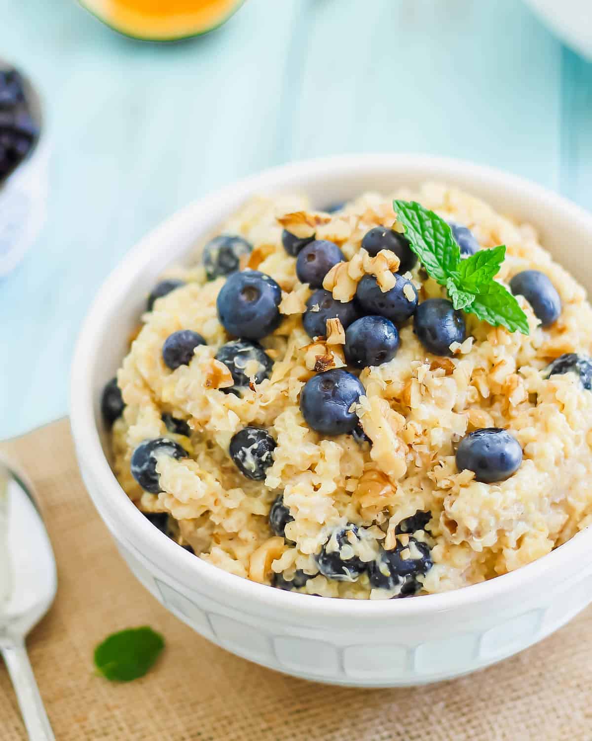 Breakfast grain bowl recipe with chopped walnuts and blueberries in a white bowl.