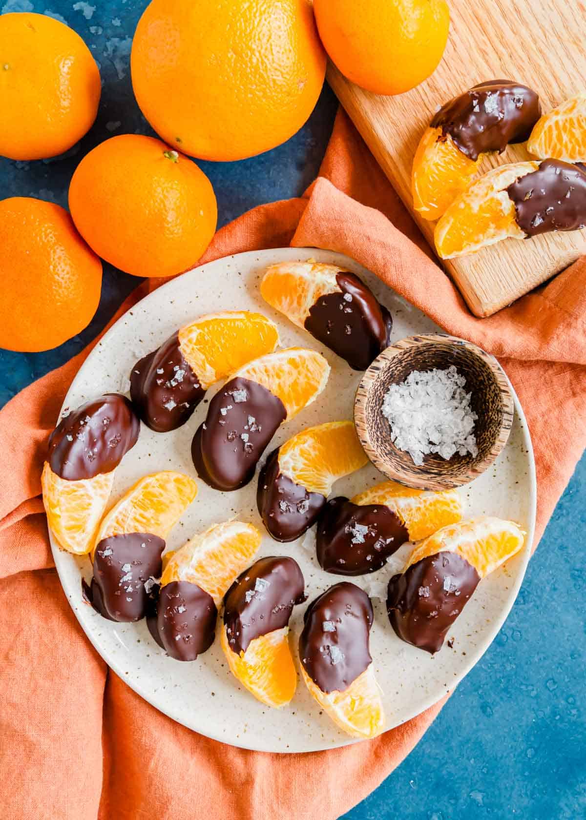 Chocolate covered oranges on a plate with flaky salt.