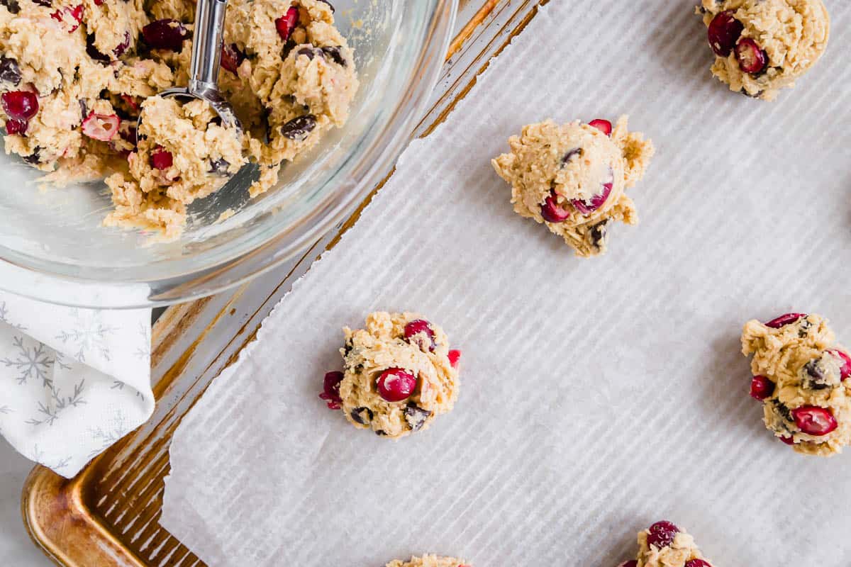 Cranberry chocolate cookie dough scooped onto a parchment lined baking sheet.