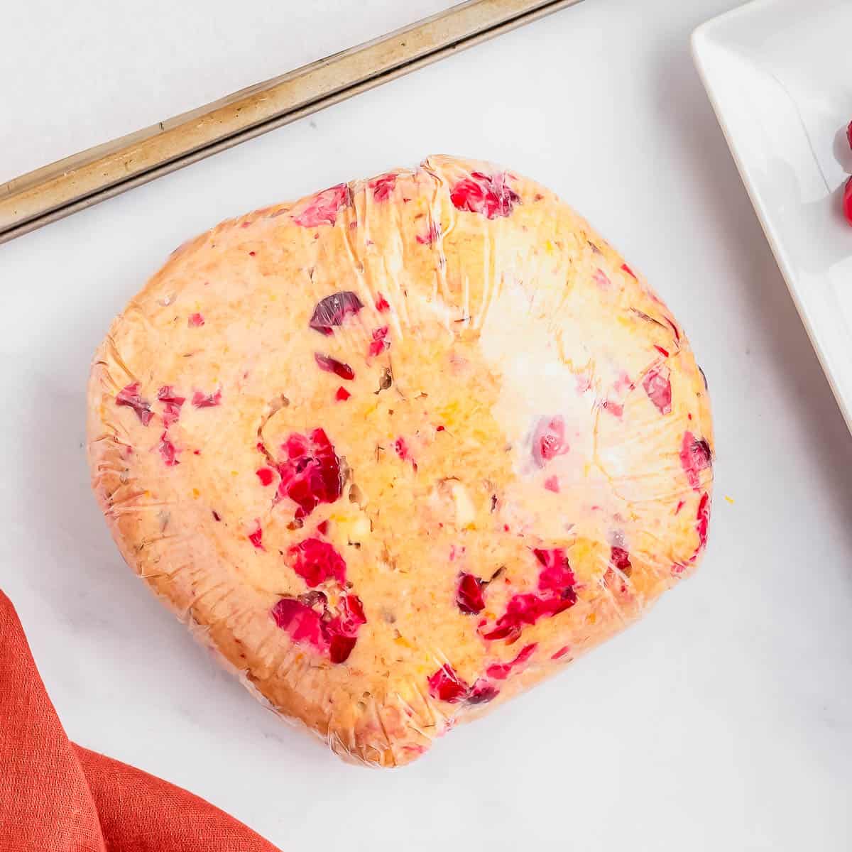 Cranberry orange biscotti dough wrapped in plastic wrap.