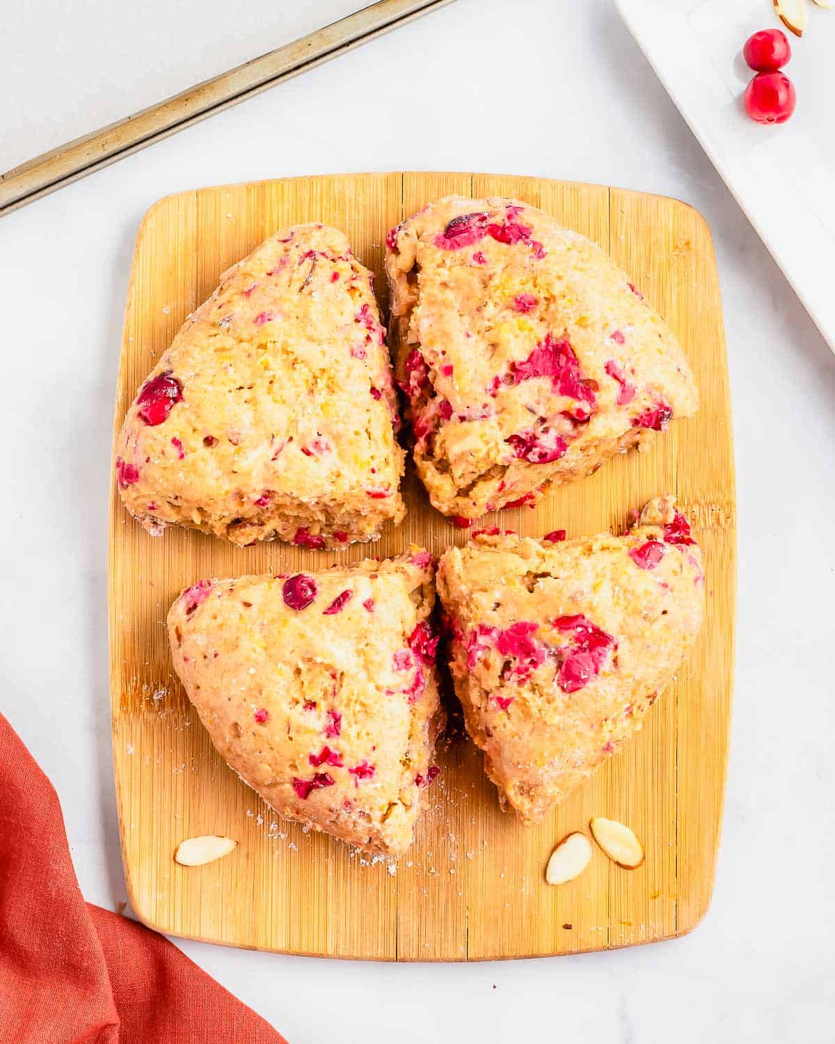 Cranberry biscotti dough cut into four equal sections on a wooden cutting board.