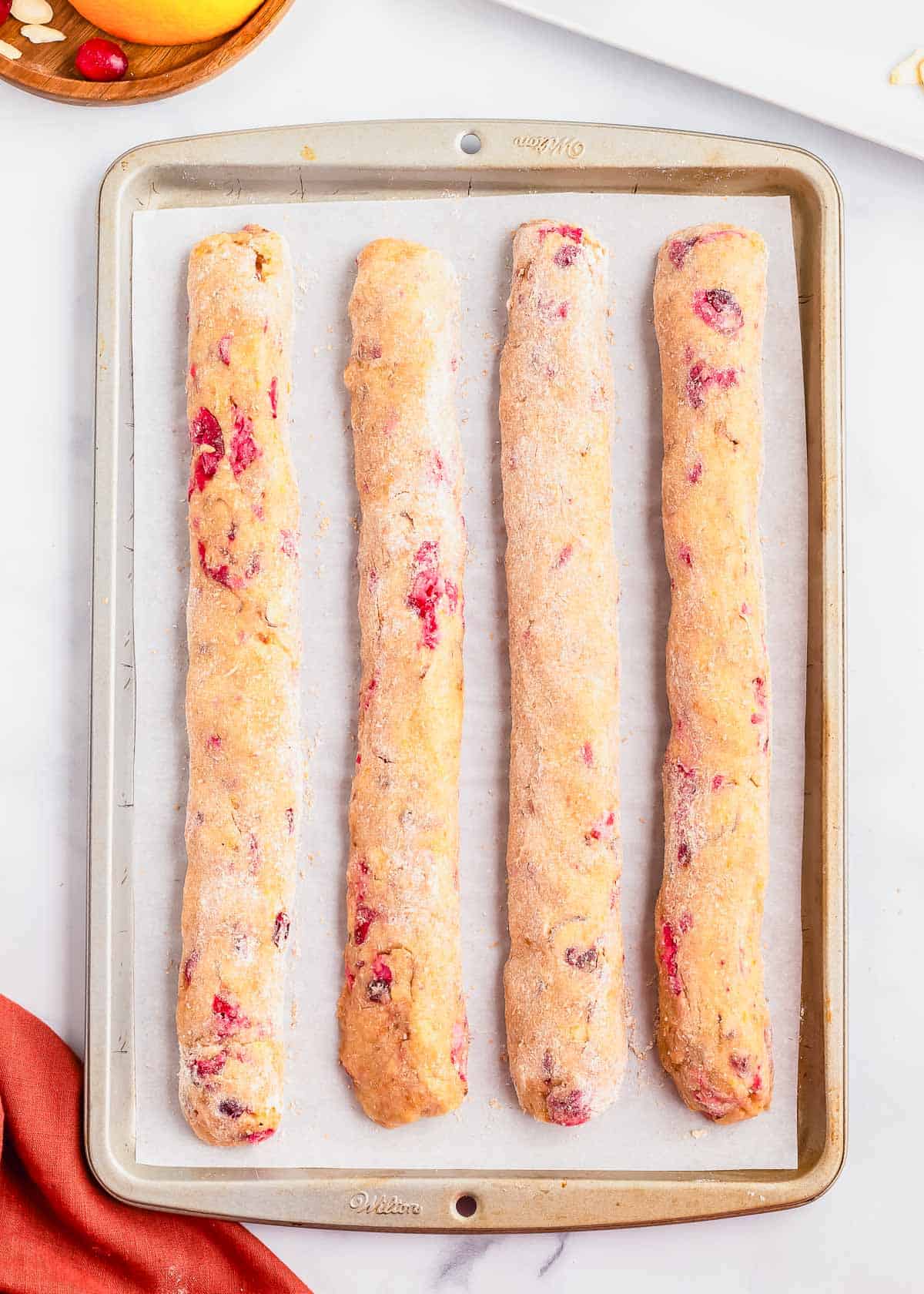 Cranberry orange biscotti dough rolled into four logs on a baking sheet.