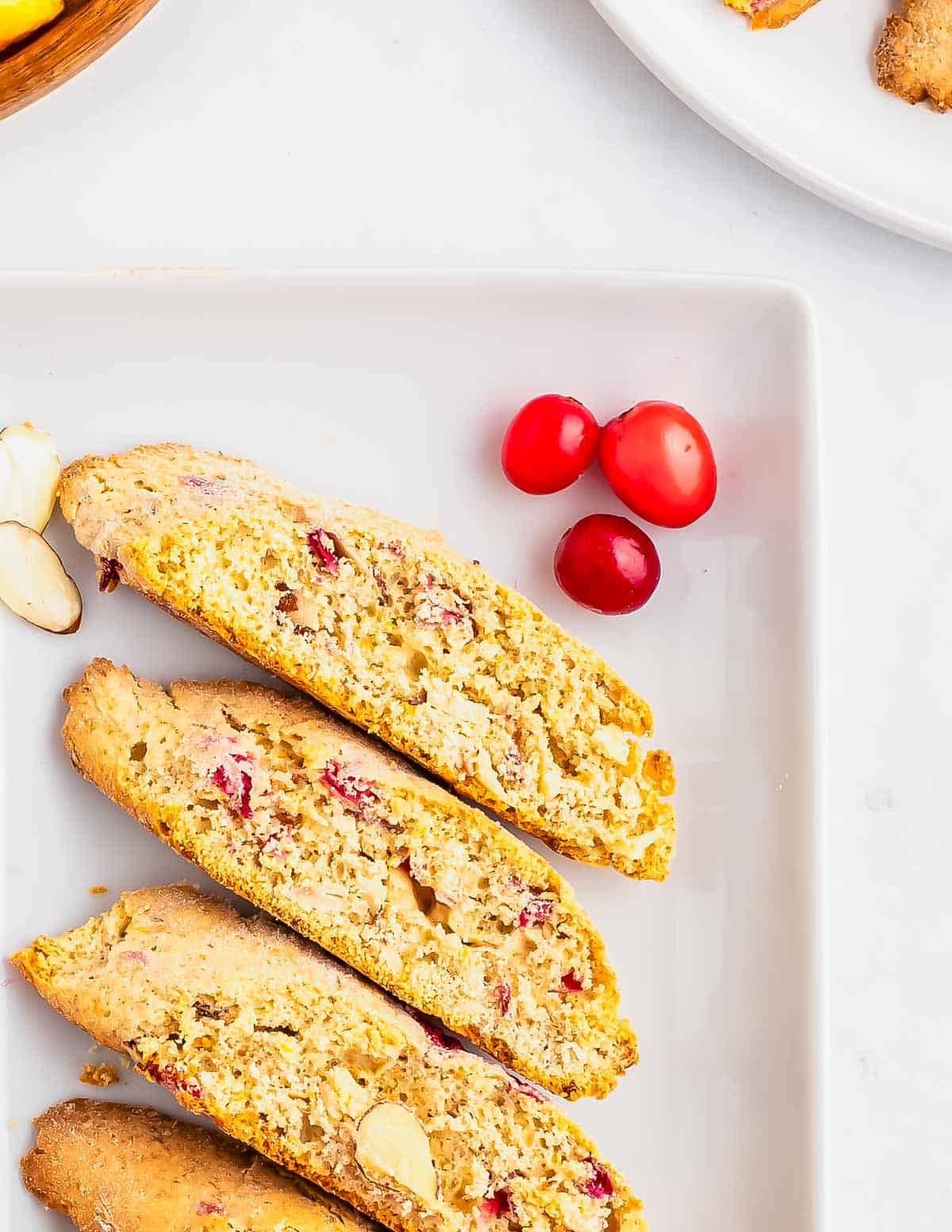 Biscotti with cranberries, oranges and almonds on a white plate.