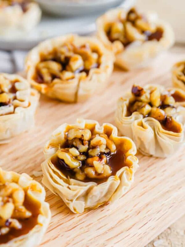 Pumpkin pie bites lined up on a wooden cutting board.