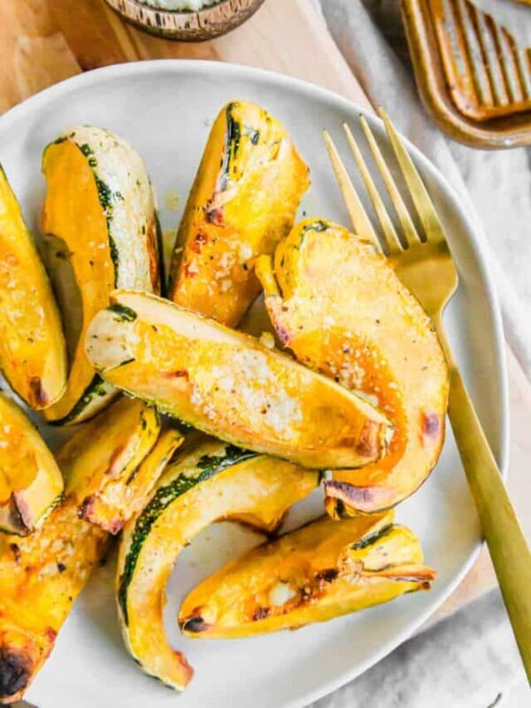 Roasted carnival squash piled on top of a plate with a gold fork.