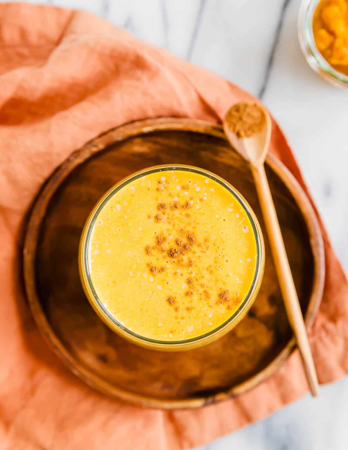 Overhead shot of a pumpkin banana smoothie in a glass dusted with cinnamon.
