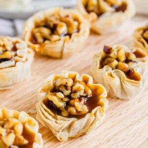 Pumpkin pie bites lined up on a wooden cutting board.