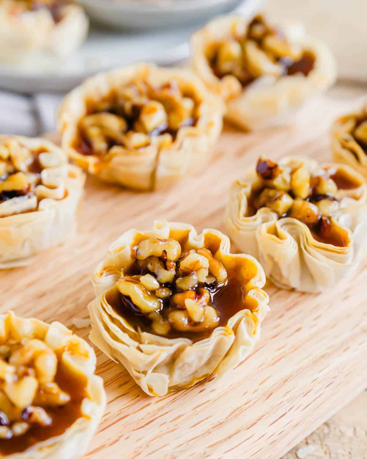 Pumpkin pie bites lined up on a wooden cutting board.