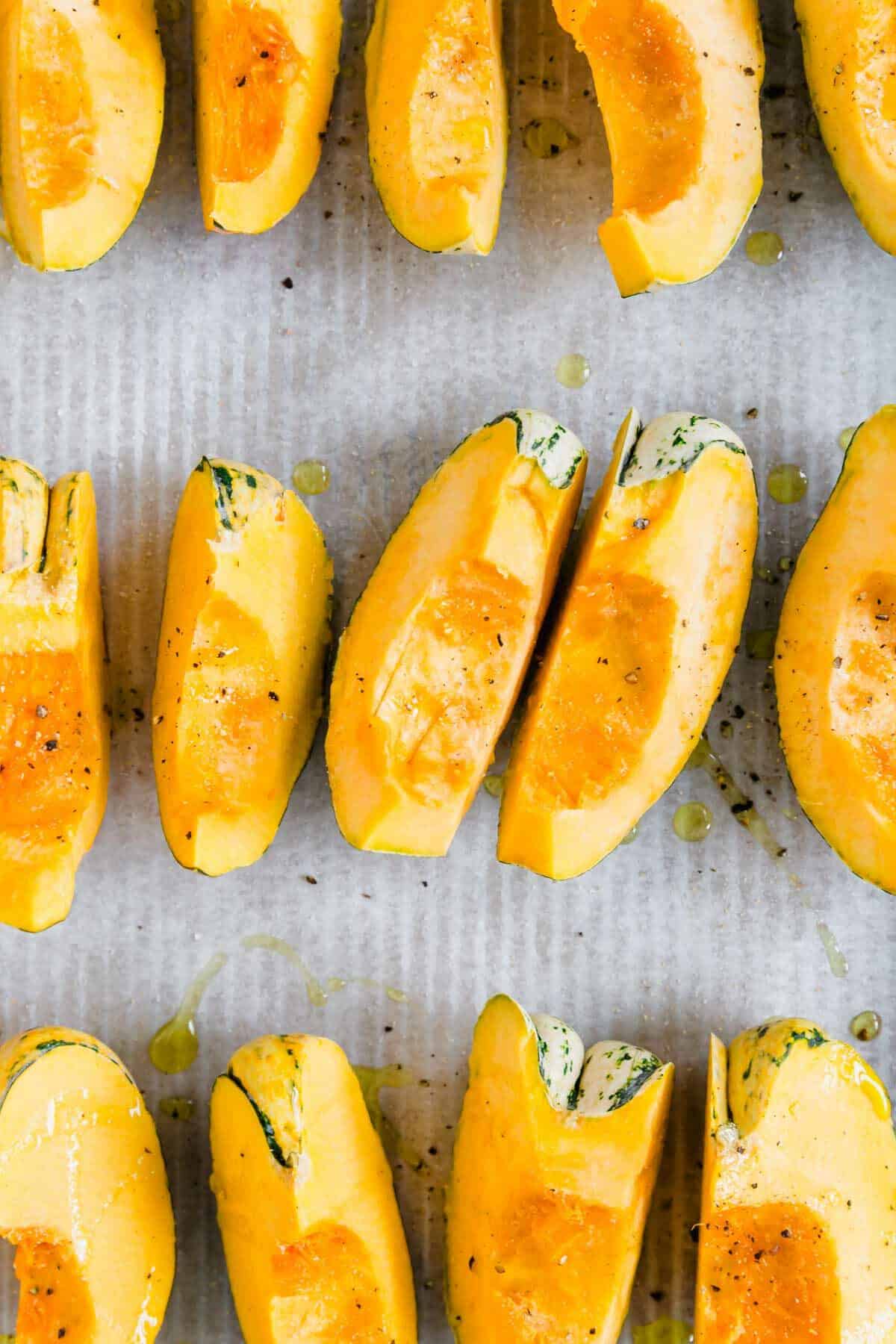 Carnival squash wedges on a baking sheet lined with parchment paper.