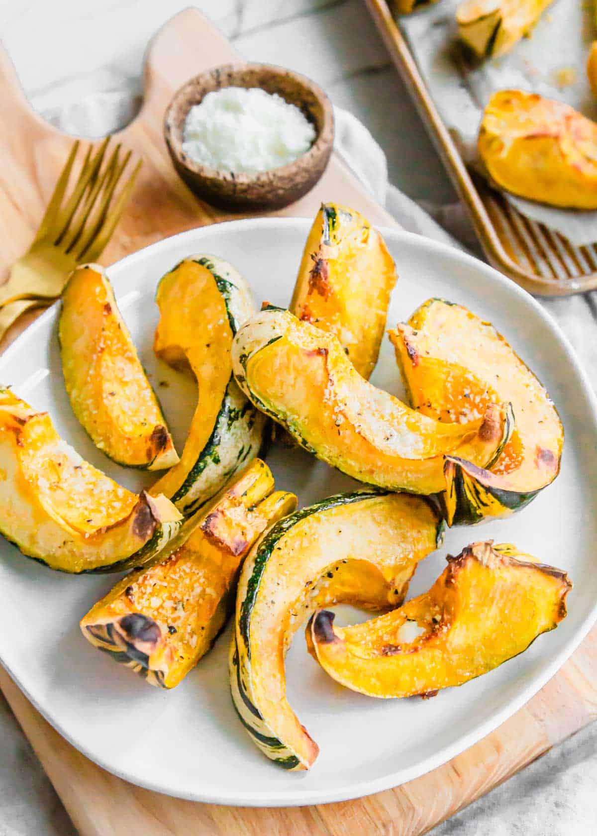 Garlic parmesan roasted carnival squash wedges on a serving plate.