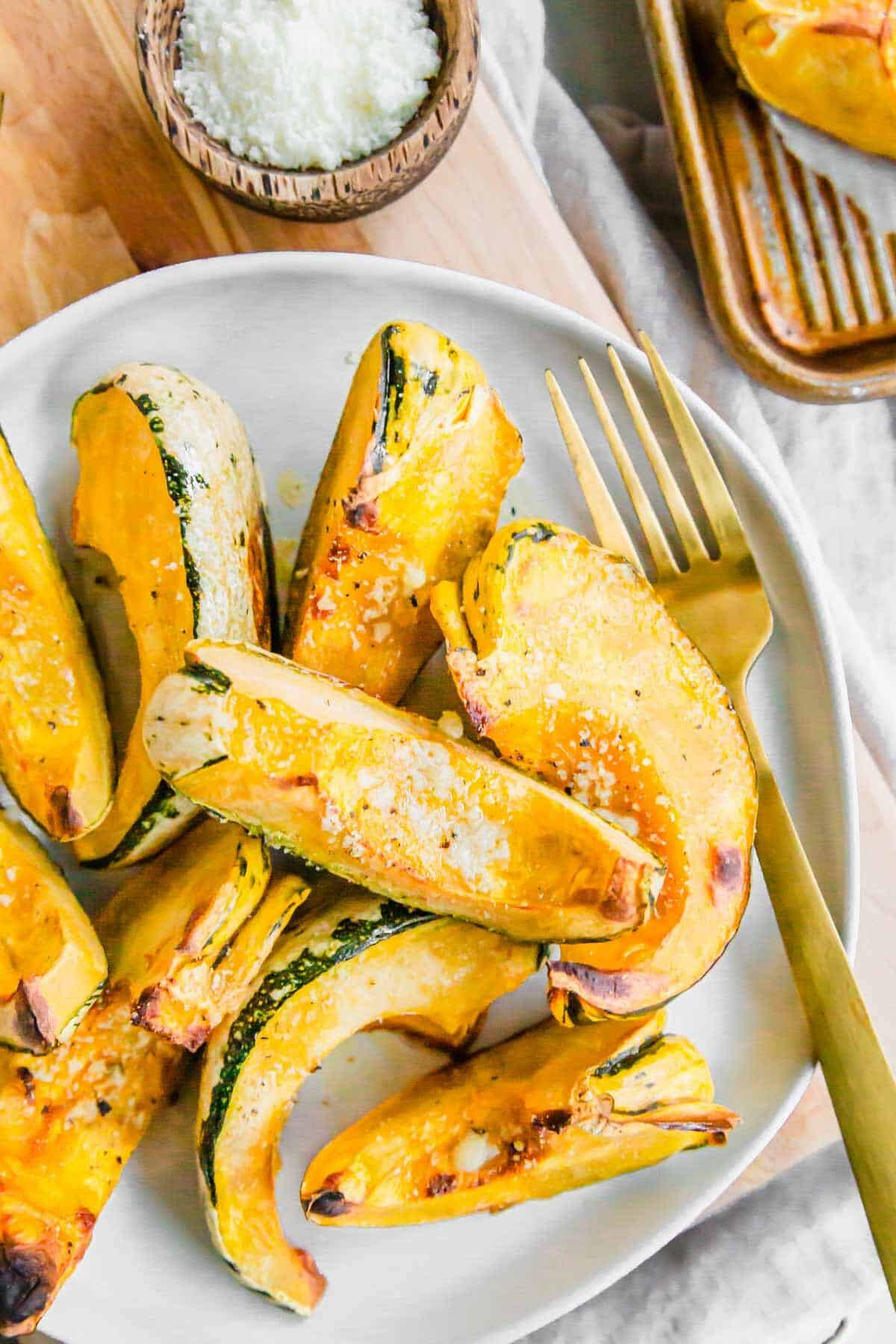 Roasted carnival squash piled on top of a plate with a gold fork.