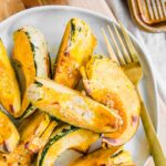 Roasted carnival squash piled on top of a plate with a gold fork.