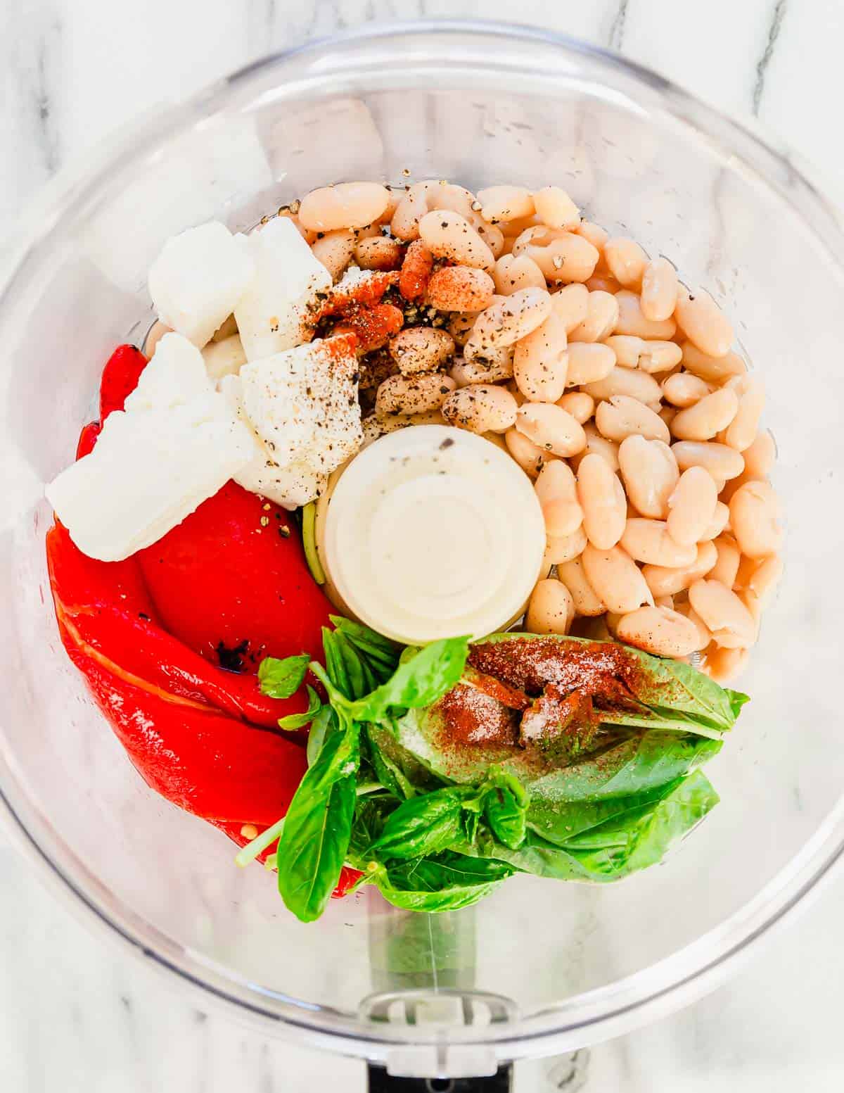 Ingredients to make roasted red pepper dip in a food processor.