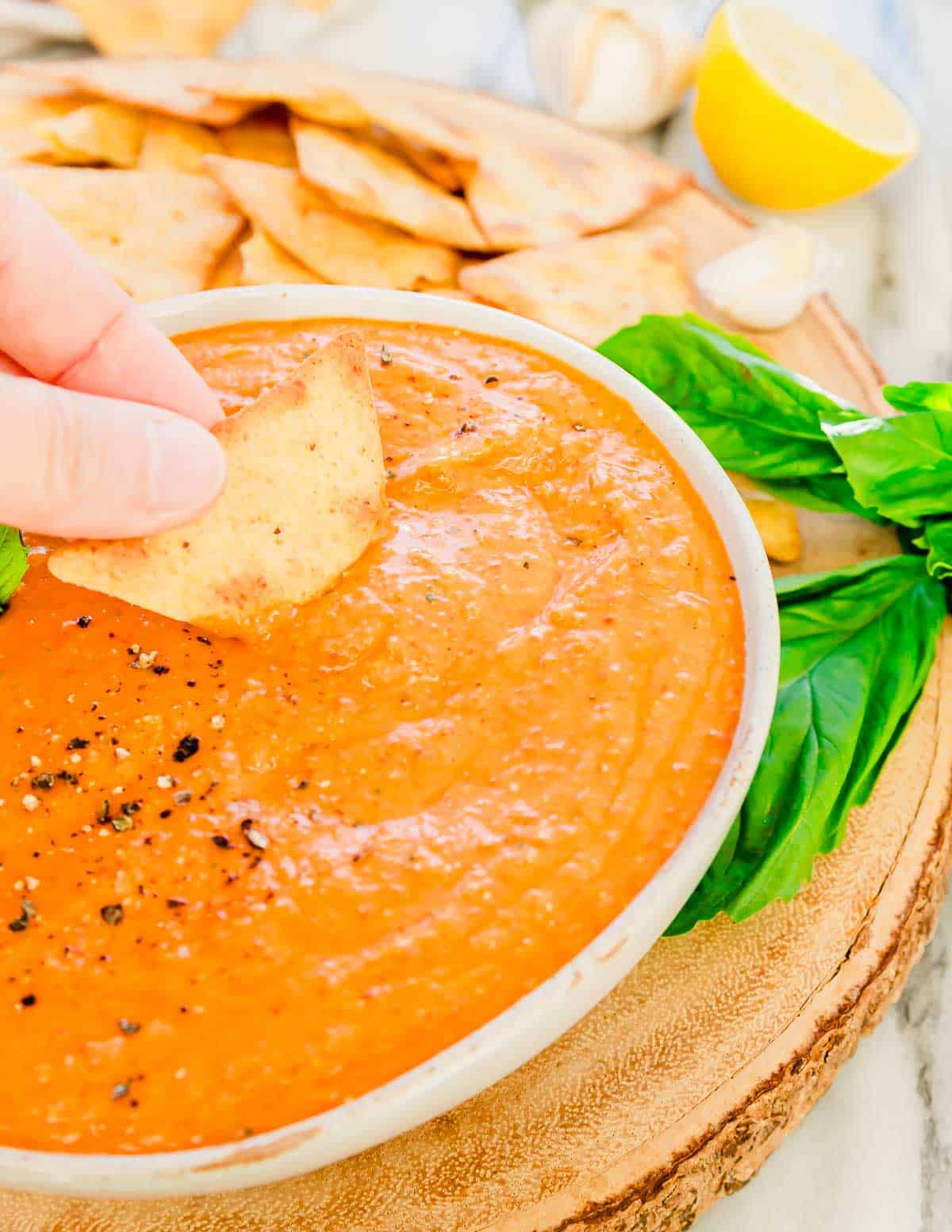 Dipping a cracker into red pepper dip.