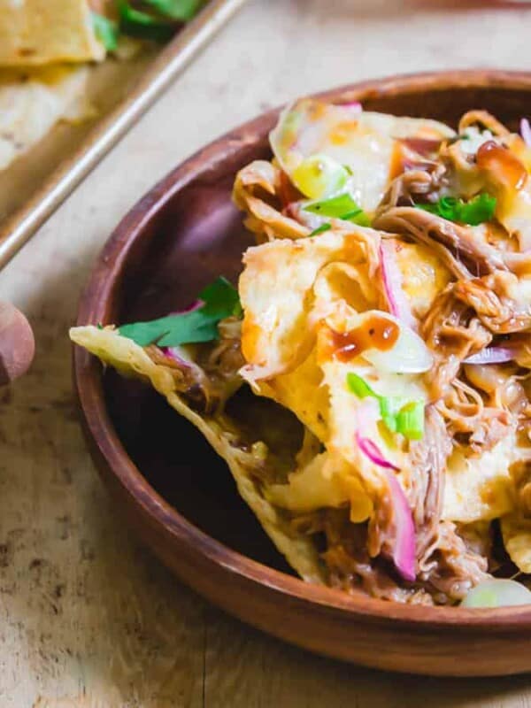 A bowl of nachos on a wooden table.
