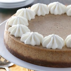 A pumpkin cheesecake on a plate with whipped cream.